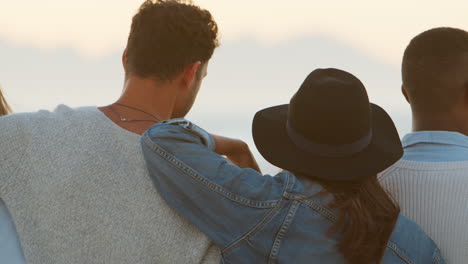 rear view of friends on winter beach watching sunrise together