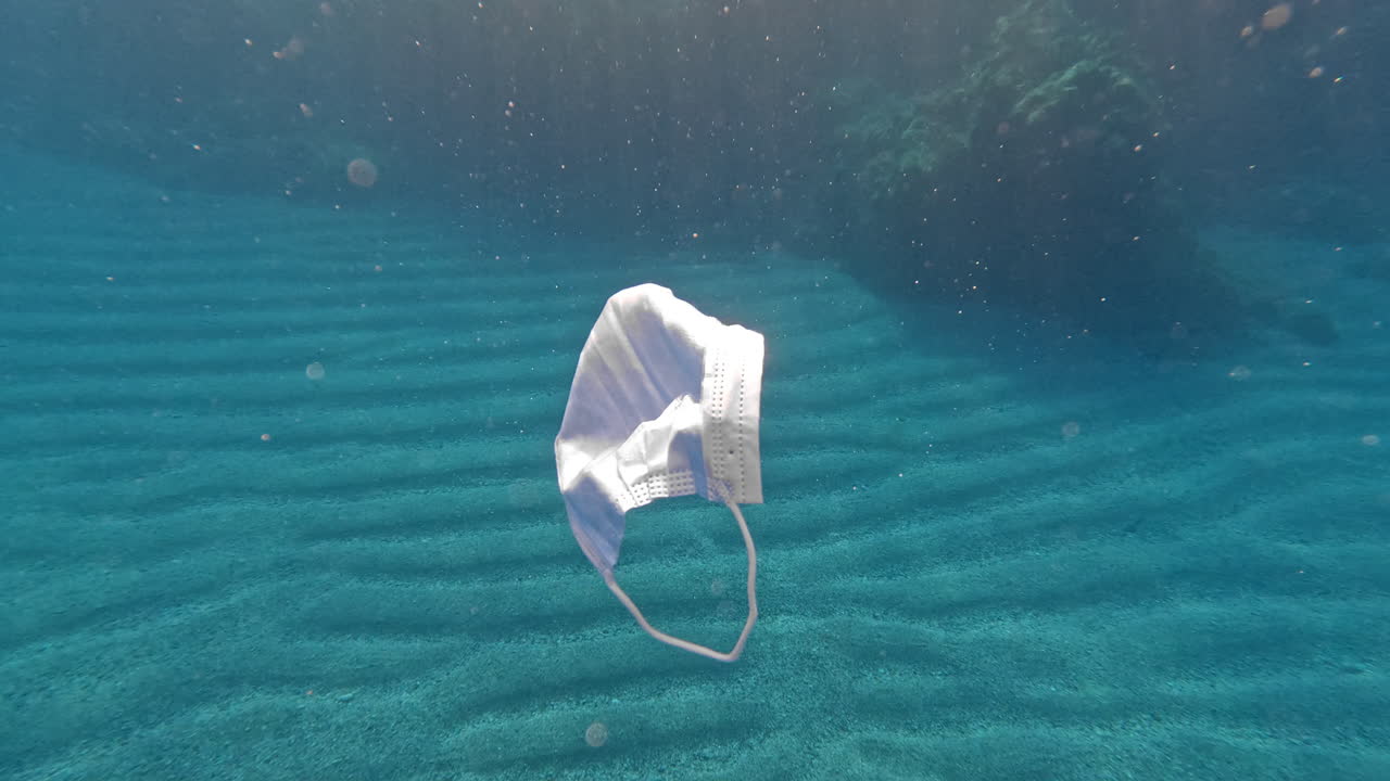 las máscaras médicas usadas están a la deriva lentamente bajo el agua