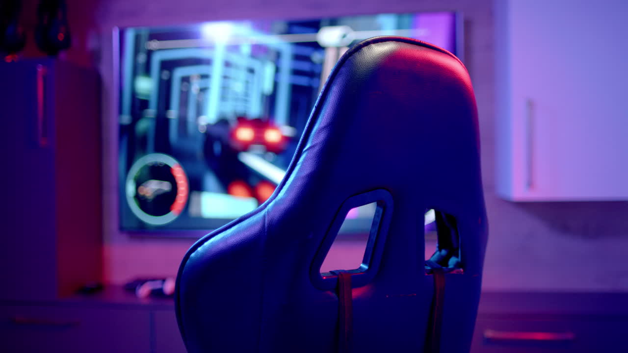A gaming chair sits empty in room lit with blue and red lights at home