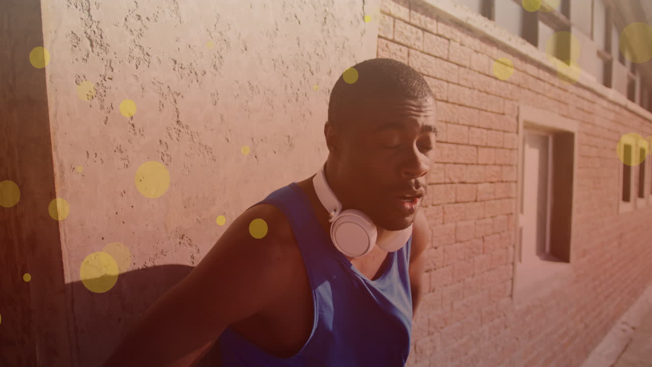 Yellow spots floating against tired african american fit man taking a break from running