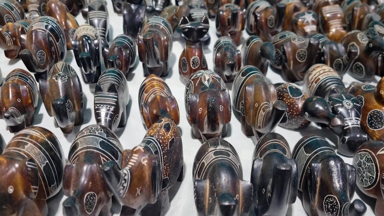 File di statuette di animali intagliate a mano sono esposte in vendita in un mercato locale a Djanet, Algeria, mostrando l'artigianato di ispirazione Tuareg e souvenir tradizionali nel cuore del Sahara