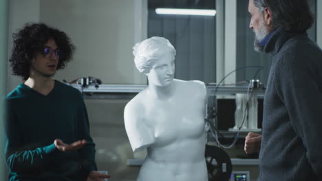designer and client discussing 3d sculpture. mature customer discussing plastic classic statue with young male designer then men shaking hands in agreement during meeting in 3d printing studio