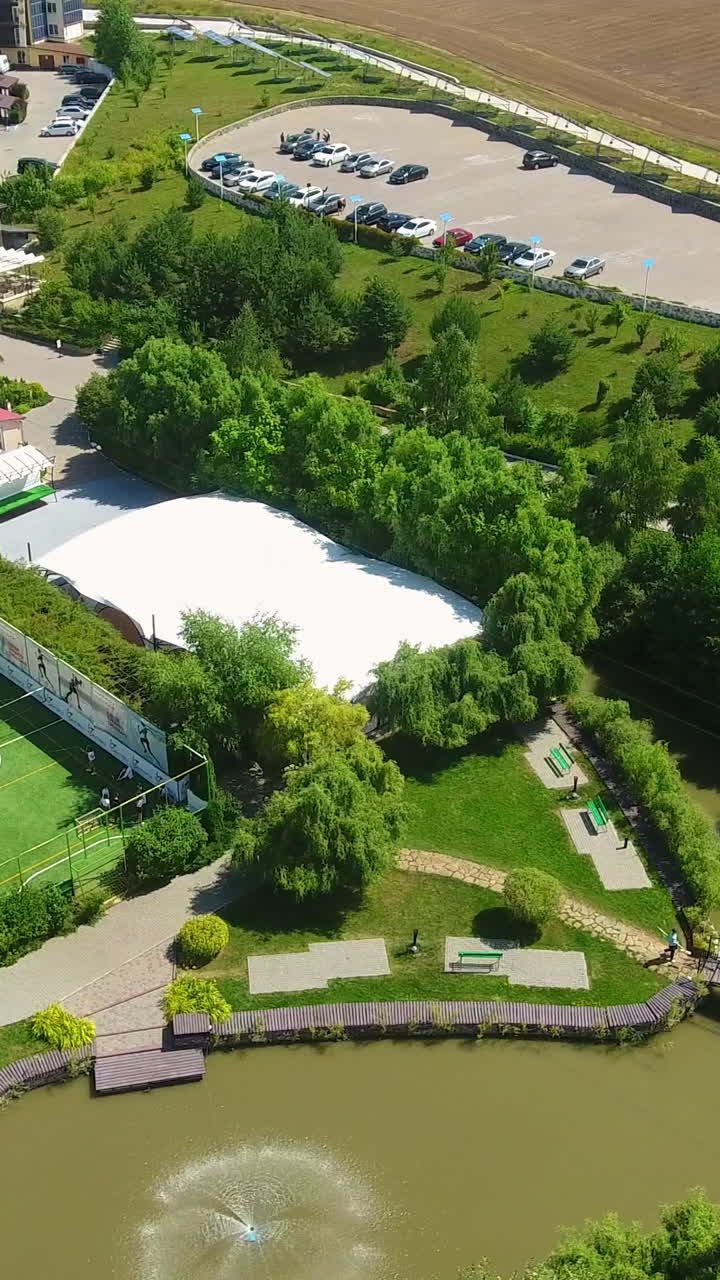 Recreational zone with private bungalows, swimming pools, tennis court and children playgrounds. People walking and resting in rural area. Top view. Vertical video