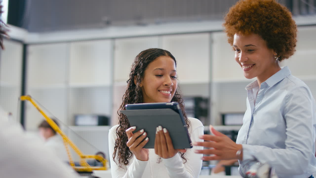 Female Teacher With Female High School Student Using Digital Tablet In STEM Class