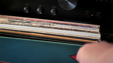 cerrar las manos del hombre hojeando discos de vinilo antiguos en casa