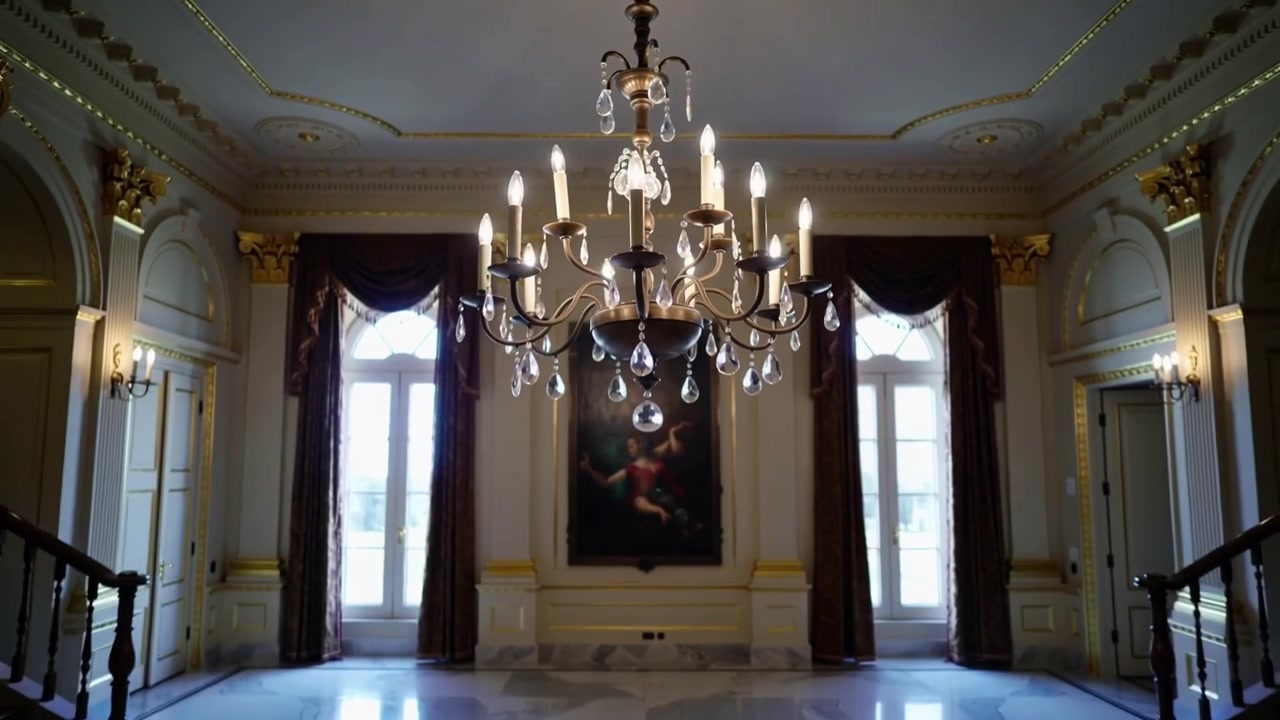 Telecamera che si allontana rivelando un lampadario in ottone che illumina la sala padronale con pendenti di cristallo
