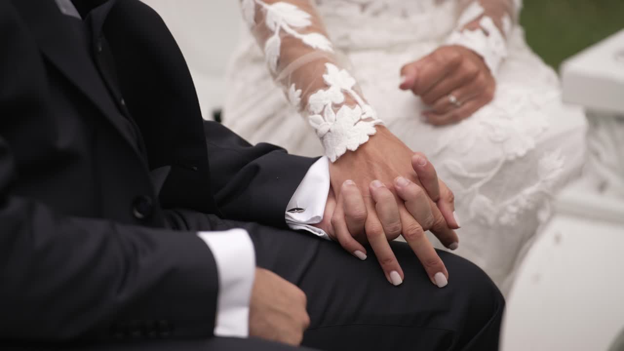 Bride and groom holding hands, focusing on the bride's lace sleeve and wedding attire