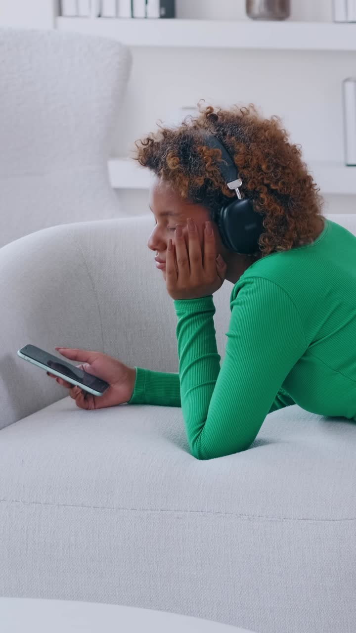 Ung kvinne lytter til musikk mens hun slapper av på en myk sofa