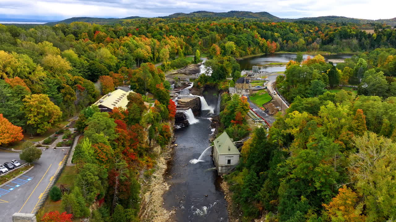 Flight above the arch bridge approaching the waterfalls in Ausable Chasm in Adirondacks. Beautiful forest changing colors in autumn around.