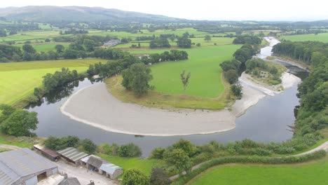 Beautiful-drone-footage-slowly-Ascending-too-400-feet-and-reversing-revealing-a-shallow,-slow-moving-meandering-river-in-rural-Lake-District,-UK