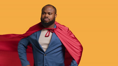 man wearing cloak posing as superhero in costume, studio background