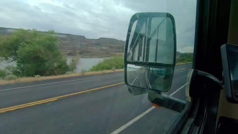 POV-of-the-driver-of-a-parked-Class-A-RV,-point-of-view-of-Blue-Lake-and-traffic-on-Highway-17-in-Washington-State-on-a-cloudy,-windy-day