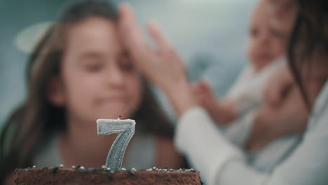 chica soplando una vela en el pastel de cumpleaños en una fiesta familiar. niño feliz cumpleaños
