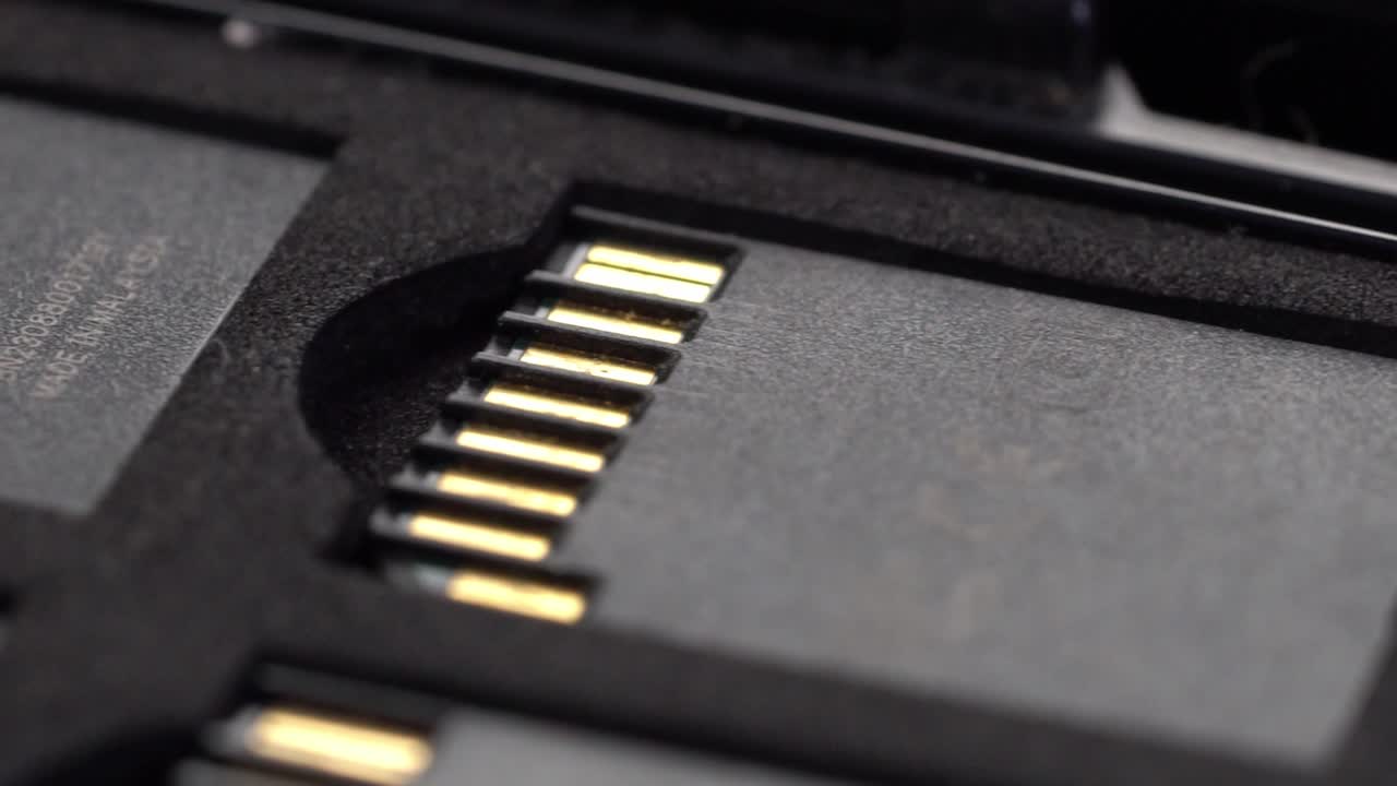 Macro shot of SD memory card showing golden connector pins inside protective case