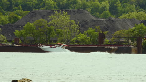 a small power boat cruises down the river near an industrial area in pennsylvania on the ohio river