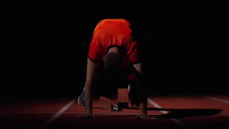 atleta preparándose para una carrera por la noche en una pista