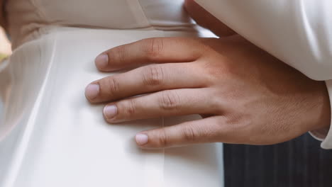 groom touches waist of woman wearing elegant white dress