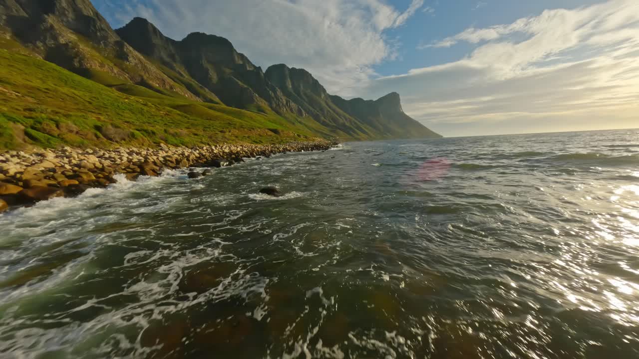drone volant bas au-dessus des vagues avec à l'arrière-plan les belles falaises de la baie de kogel
