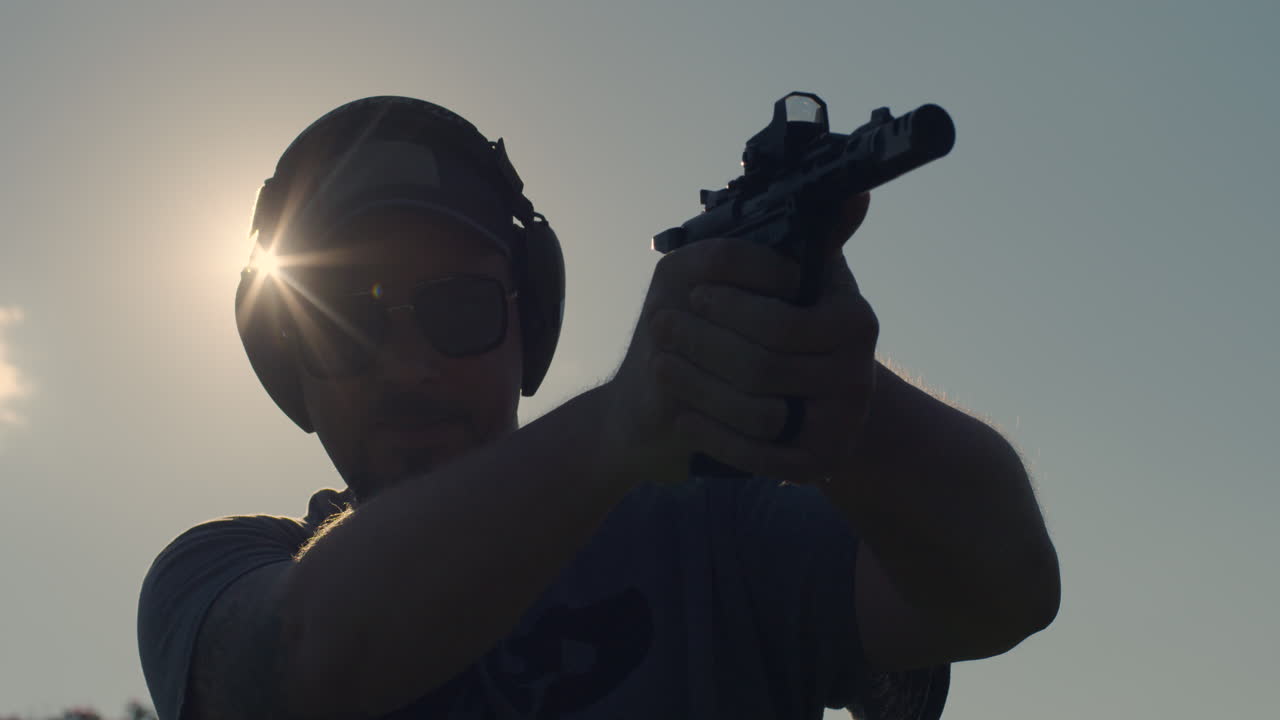 Man Firing Pistol In Silhouette With Sunburst