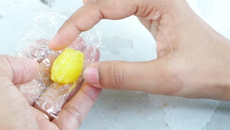 hand unwrapping a yellow candy