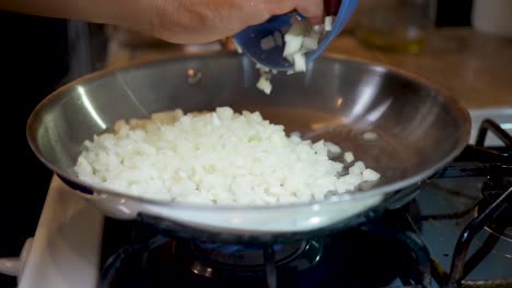 tirando cebollas en dados en una sartén caliente y aceitada sobre la estufa - cámara lenta