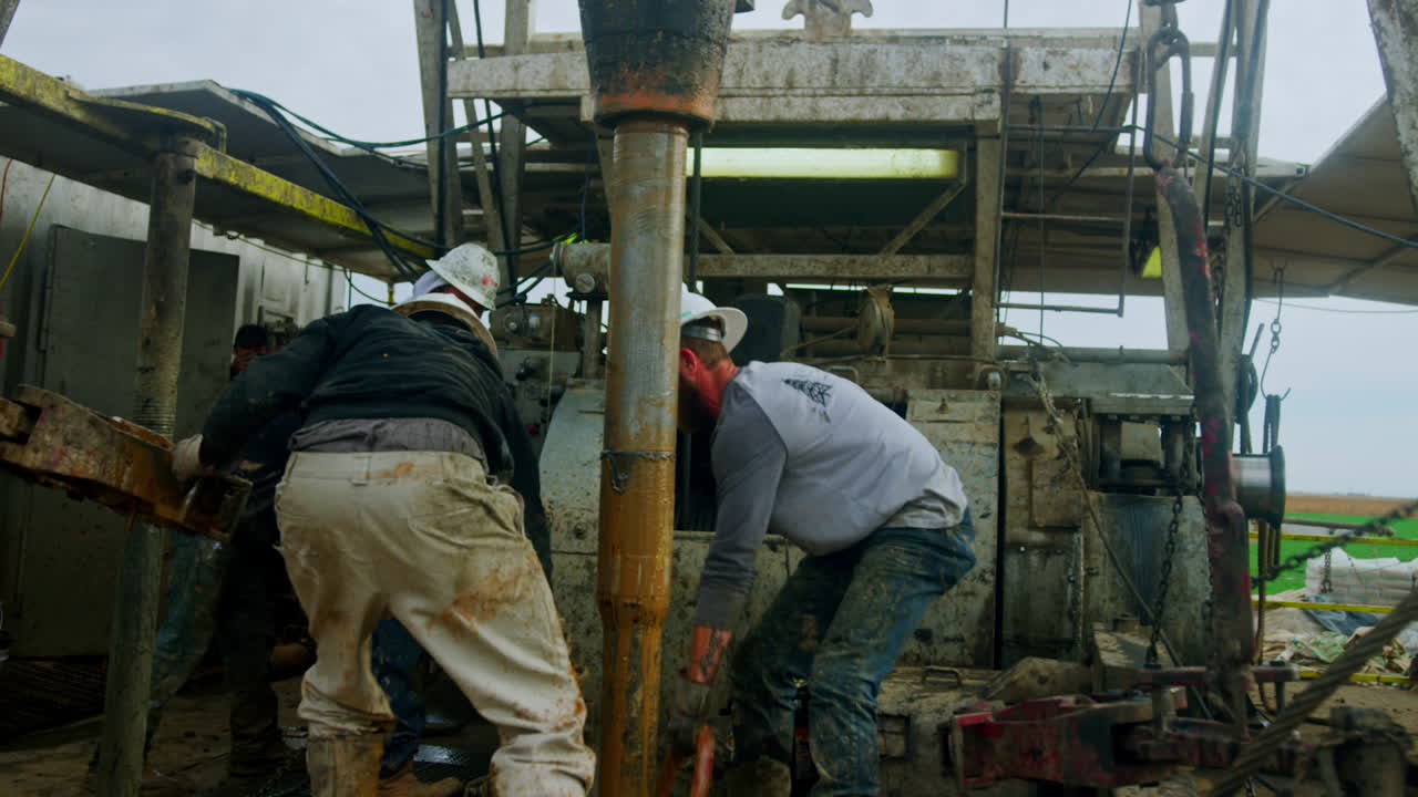 Team of hard-working men at the drilling oil site. Workers set and maintain the machines for resources boring.