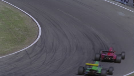 three cars race around a track