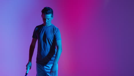 Studio-Portrait-Of-Male-Tennis-Player-Bouncing-Ball-On-Racket-Preparing-To-Serve-Against-Low-Key-Colourful-Mixed-Lighting-1