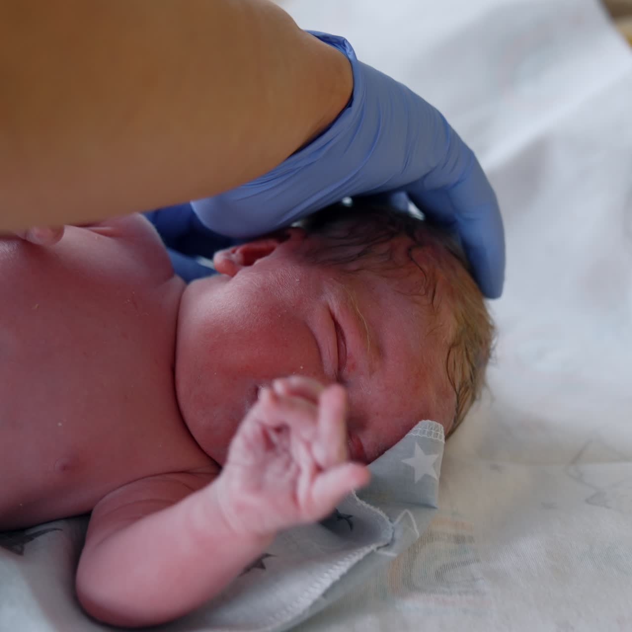 Newborn cries and waves his hands while being checked by the doctor. Medic uses measuring tape to know child's length. Close up