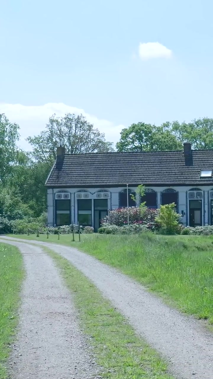 Tradisjonelt nederlandsk gårdshus omgitt av frodig grønt og trær