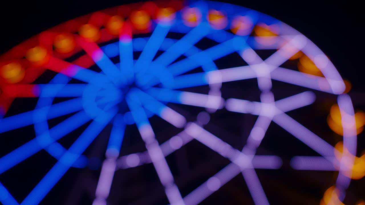 Blurred Ferris wheel with colourful lights at night