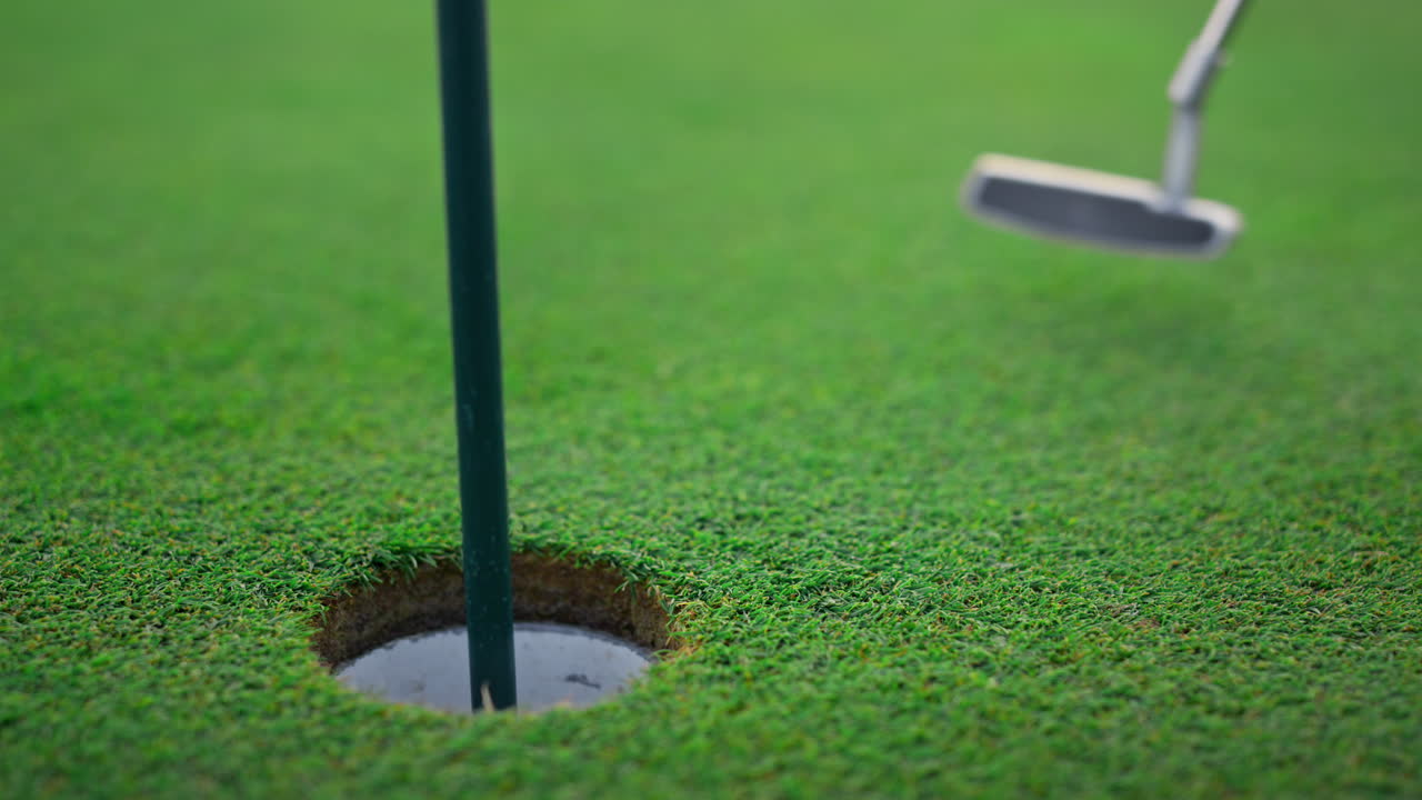 골프 클럽이 코스 구 ⁇ 에서 공을 치고 골프 선수가 페어웨이에서 푸터를 흔들고 있습니다.