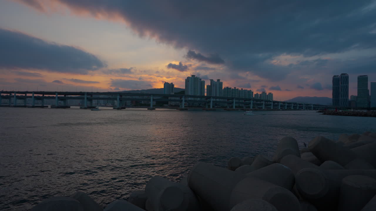 Seafront View of Gwangan Bridge in Blue Hour Sunset Sunlight in Busan and Downtown Apartment Buildings in Backdrop