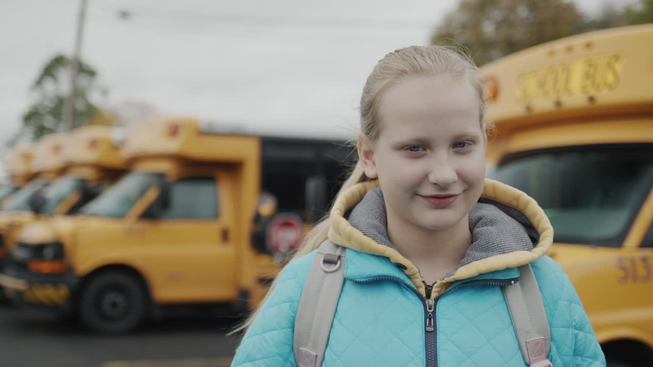 портрет студентки на фоне типичного желтого школьного автобуса