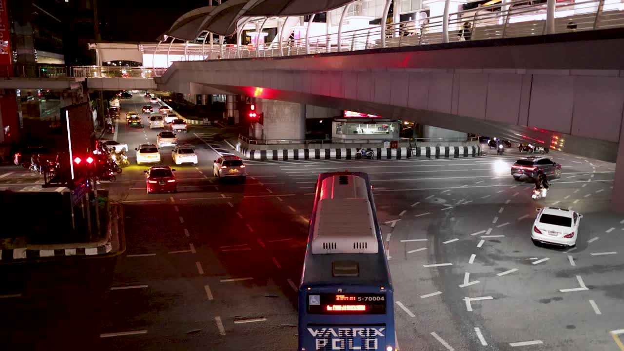 Urban intersection with cars, motorcycles, and city bus under artificial lighting, overhead camera angle