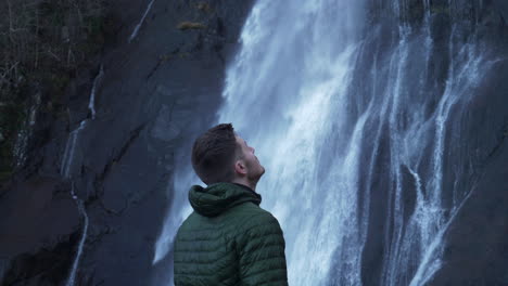 Hiker-Man-Looking-Up-At-A-Waterfall-Hiking-In-Scotland