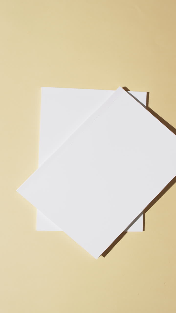 Vertical video of books with blank white pages and copy space on yellow background