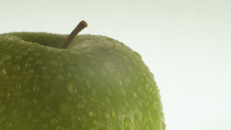 close up shot of an green apple with water drops on it