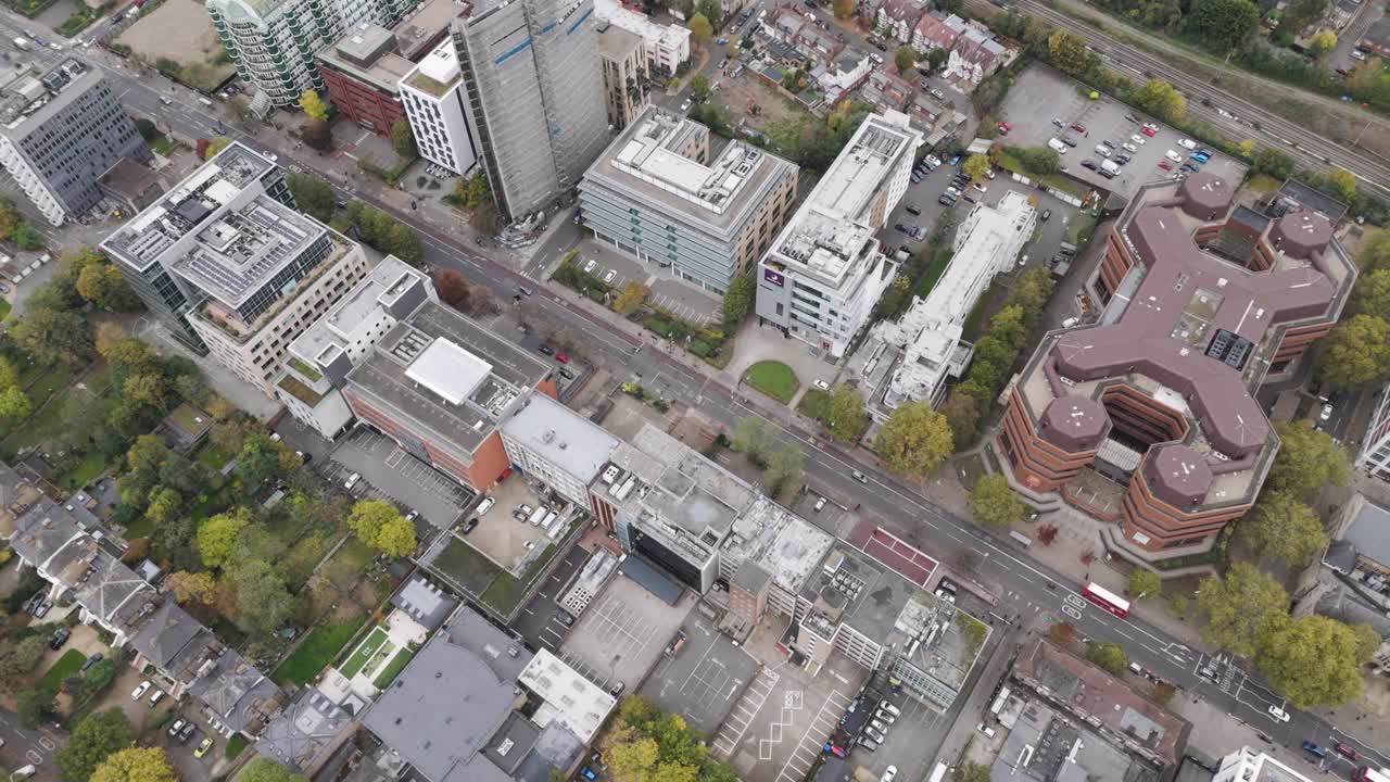 Dynamic aerial sweep of commercial district featuring diverse office buildings along Uxbridge Road, Ealing, London, UK, October 2024