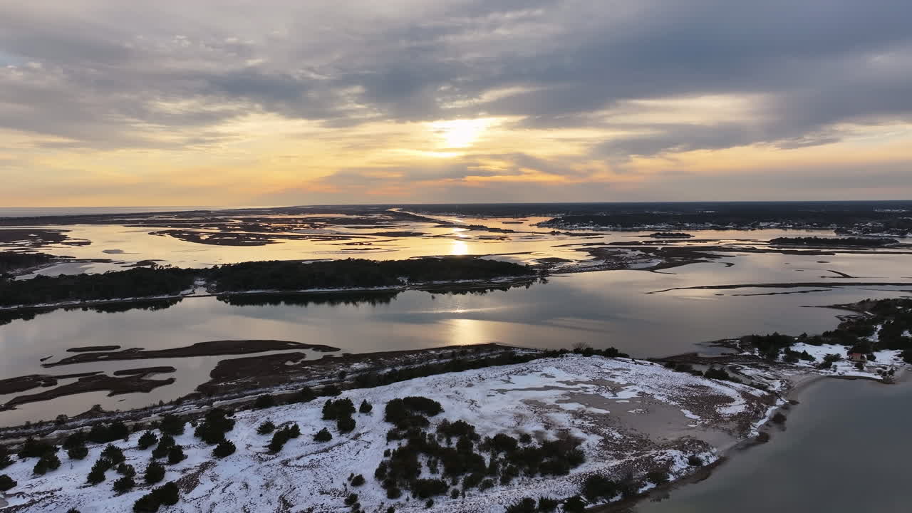 Luftaufnahme der Crystal Coast Barriereinseln, wo seltener Schneefall sandige Küstenlinien bedeckt und Eis über die Küstensümpfe zieht. Drohnenaufnahme.