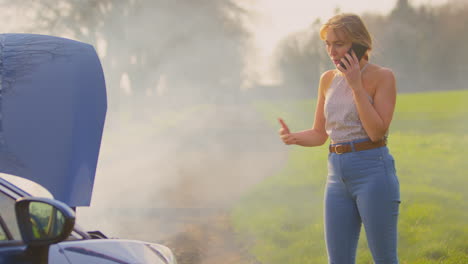 mujer frustrada con un coche averiado en una carretera de campo pidiendo ayuda por teléfono móvil