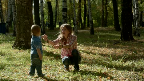 loving son brings smth to his happy mother and hugs her in park