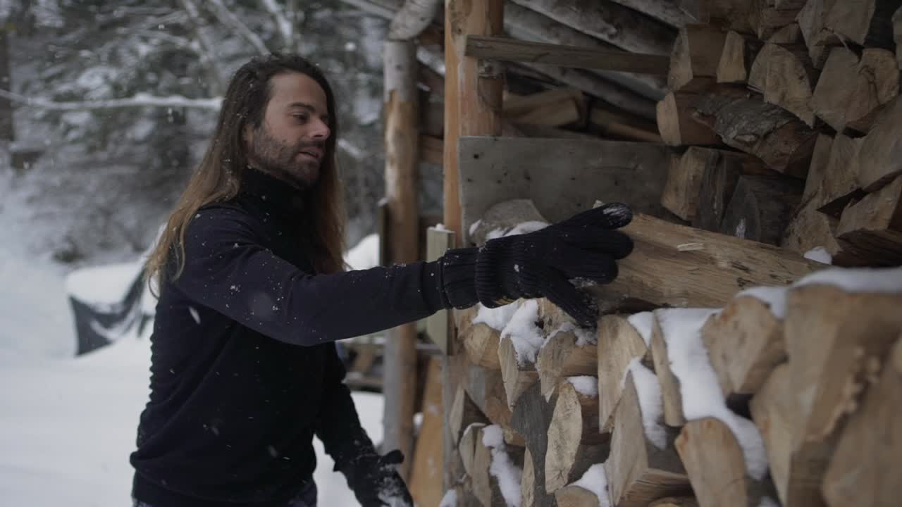 Male taking firewood from shed in winter