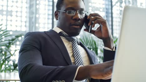 african manager working on laptop and using phone