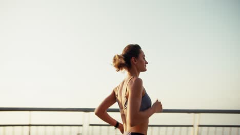 happy girl in a sports top on a morning run. young fit girl running against the backdrop of sunrise