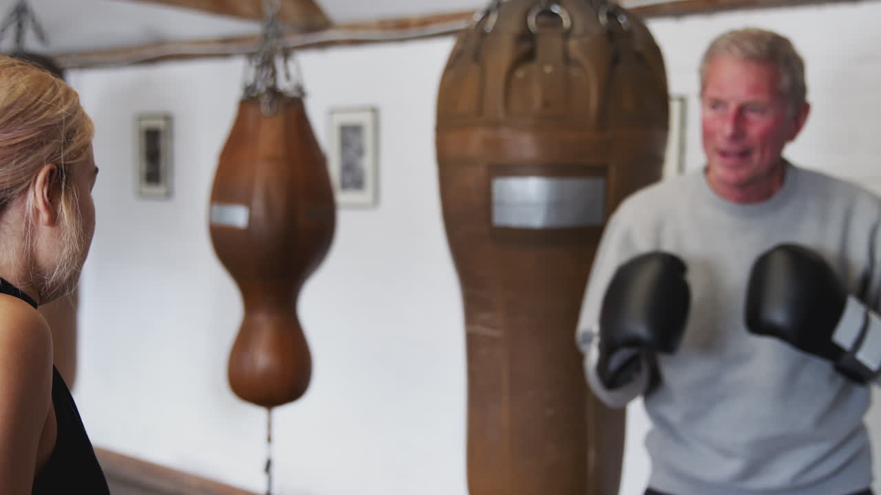 훈련 장갑 을 사용 하는 체육관 에서 젊은 여자 코치 와 함께 시니어 남자 권투 선수