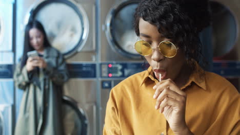 young pretty and stylish girl in yellow glasses siting in laundry service room