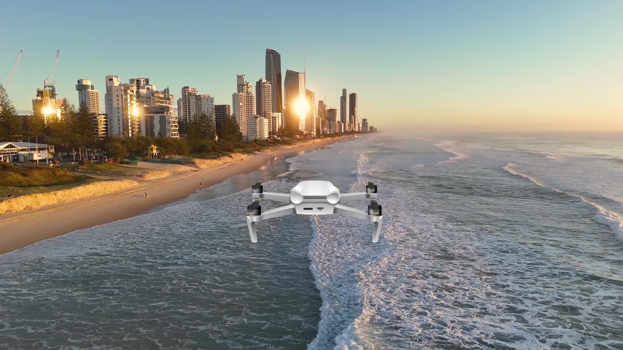 Aerial animation of a drone flying over a city beach, capturing sunrise reflections on skyscrapers and ocean waves