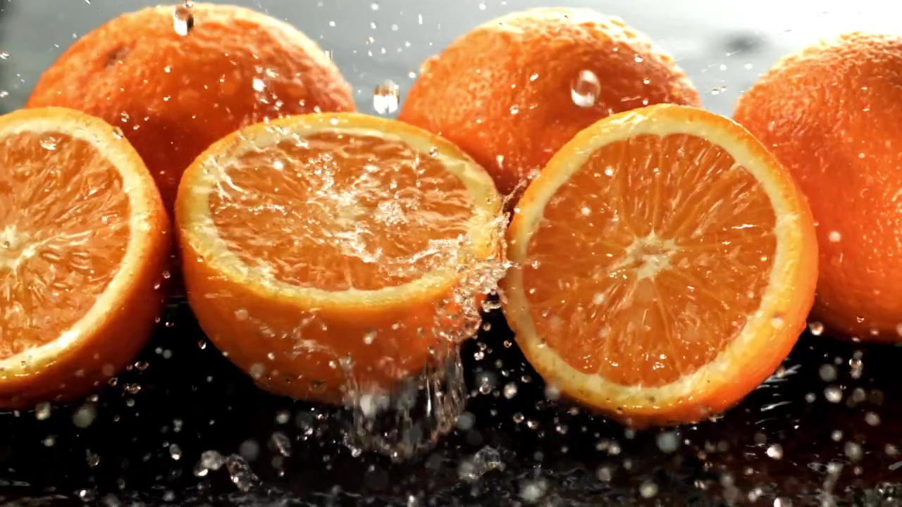 Acqua che schizza su arance fresche e fette al rallentatore