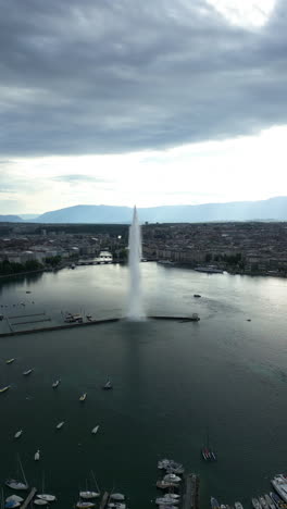 vertical, aerial: parallax drone shot of water fountain of geneva during the day (rade of geneva) in canton of geneva, switzerland